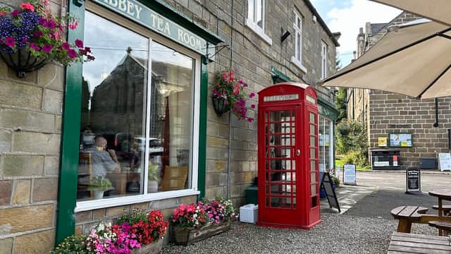 Quaint tearoom with a red phone booth, flower boxes, and outdoor seating in Rosedale Abbey, Yorkshire.