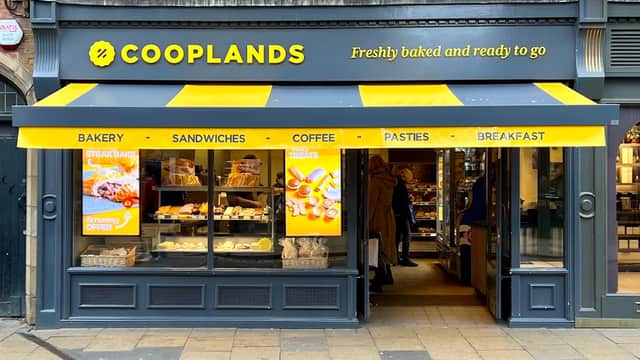Cooplands bakery storefront with yellow awning, displaying pastries, sandwiches, and coffee options.