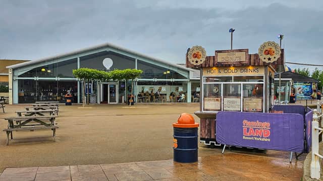Event venue with a modern glass facade, outdoor seating, and a drinks stall in front.