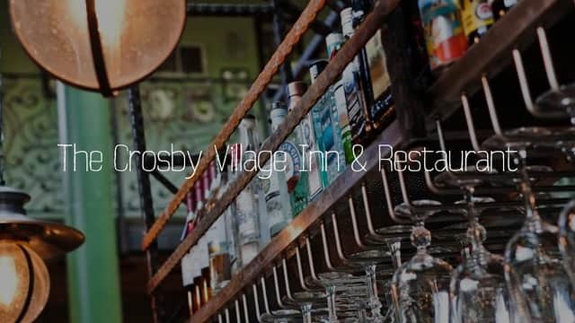 Bar shelves lined with various bottles and hanging glasses, featuring rustic decor in a cozy atmosphere.