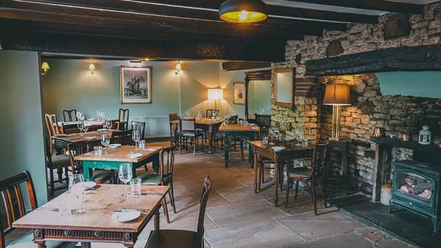 Cozy pub interior with wooden tables, chairs, stone fireplace, and soft lighting in Felixkirk, Yorkshire.