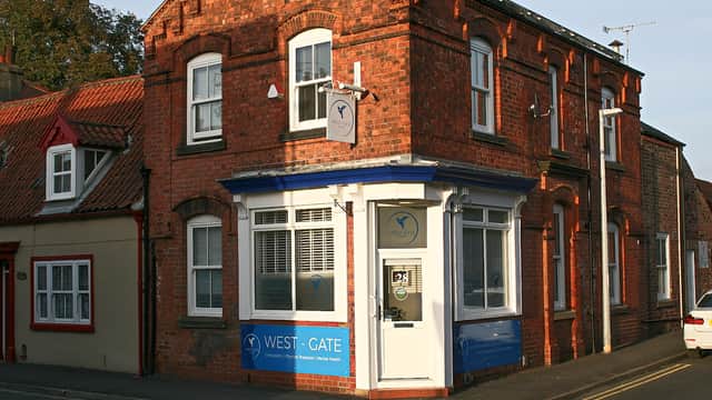 Brick building with a blue and white sign reading "WEST-GATE" and large windows, located on a street corner in Great Driffield.