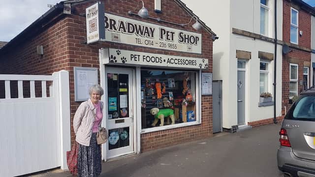 Exterior of Bradway Pet Shop with a woman standing outside, showcasing pet food and accessories in the window display.