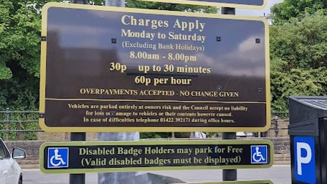 Welcome sign for Tuel Lane Car Park with parking charges and conditions displayed, surrounded by greenery.