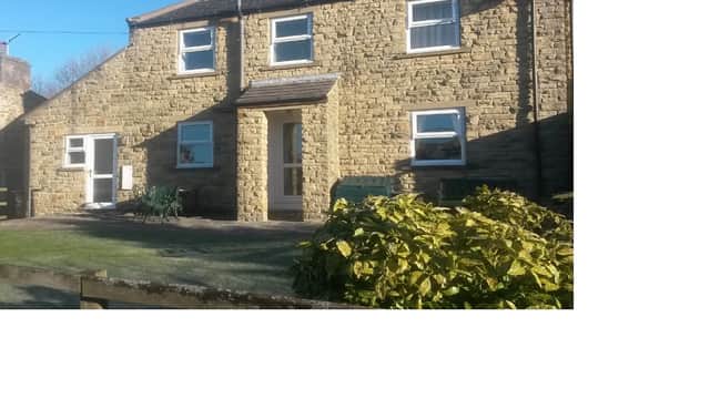 Wagtail Cottage features a stone exterior, a front door, and green seating in a garden setting in Sedbusk, Yorkshire.