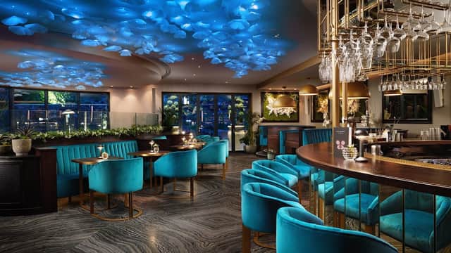 Stylish interior of Restaurant EightyEight with blue ceiling decor, elegant bar, and plush teal seating.