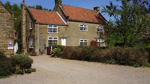 Charming stone farmhouse with a red-tiled roof, surrounded by greenery and a gravel driveway in Over Silton, Yorkshire.