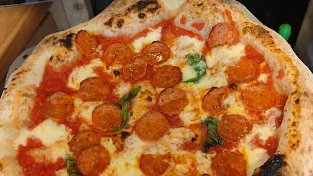 Neapolitan pizza topped with pepperoni and fresh basil, featuring a charred crust, served at The Two Tossers in Nafferton.