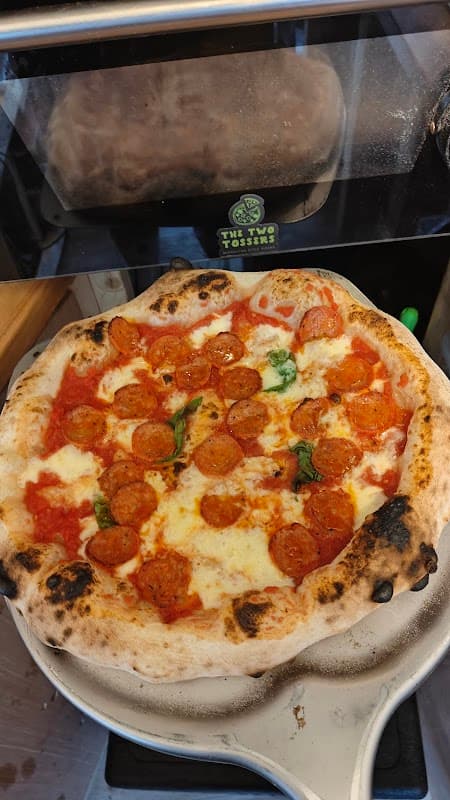 Neapolitan pizza topped with pepperoni and fresh basil, featuring a charred crust, served at The Two Tossers in Nafferton.