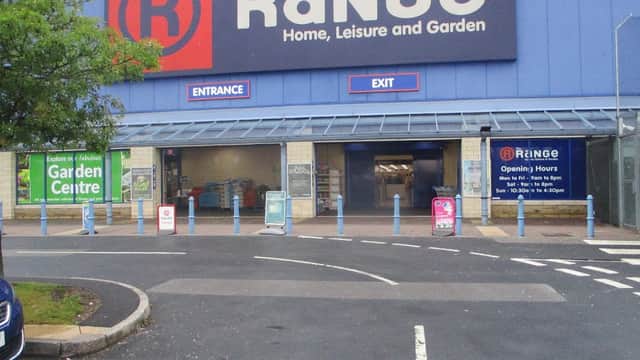 The Range store exterior with entrance and exit signs, blue barriers, and promotional banners for the garden center.