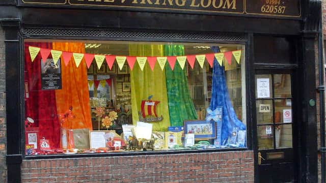 Colorful window display with fabric drapes, homeware items, and decorative banners at The Viking Loom in York.