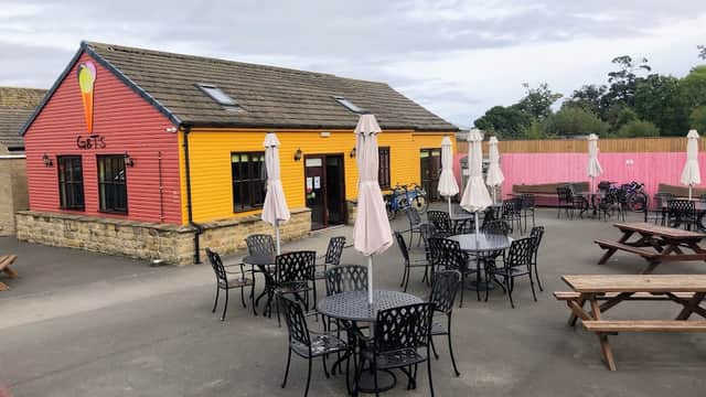 Brightly colored ice cream shop with outdoor seating and umbrellas, surrounded by a spacious patio in Risplith, Yorkshire.
