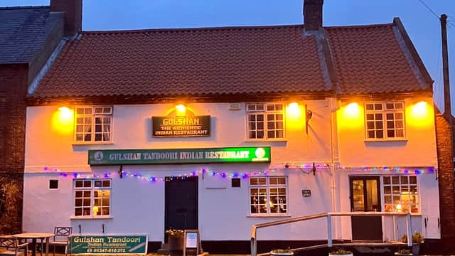 Gulshan Tandoori takeaway with warm lights, green signage, and festive decorations in Stillington, Yorkshire.