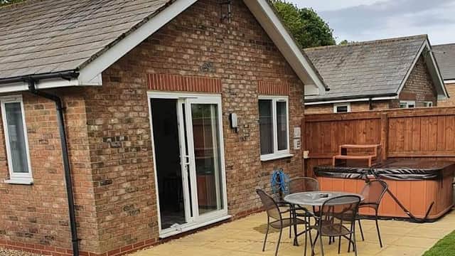 Bungalows with a patio area, outdoor seating, and a hot tub in a green space at Carnaby Covert Lane, Yorkshire.