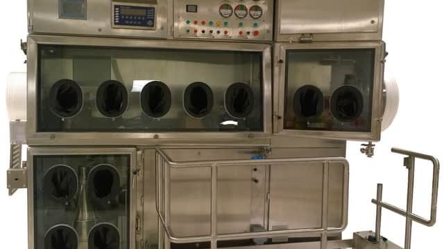 Stainless steel containment unit with multiple viewing ports and control panel, designed for handling hazardous materials.