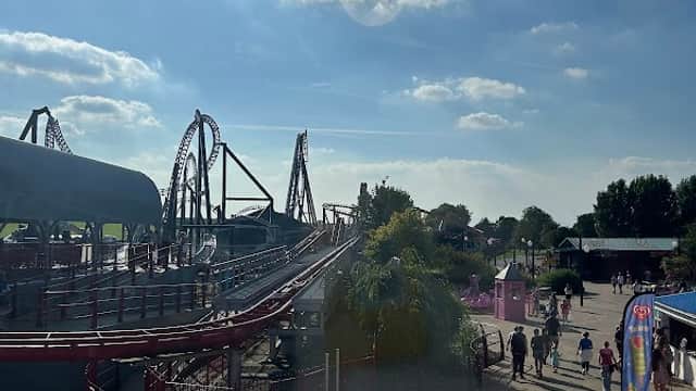A sunny day at The Splash Zone, featuring roller coasters, visitors, and vibrant attractions at Flamingo Land Resort.