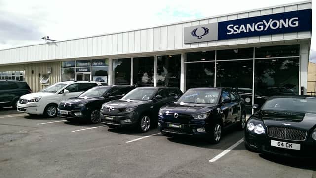 Showroom with multiple SsangYong vehicles parked outside, featuring a large glass front and signage for sales and service.