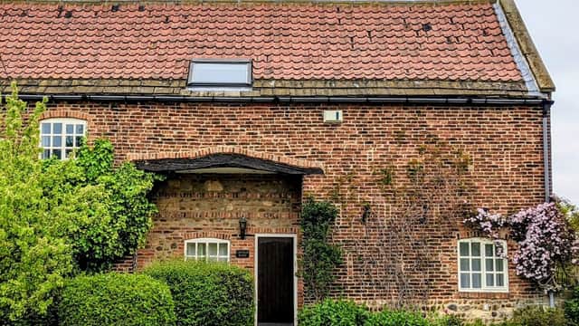Community hall with a brick facade, a red-tiled roof, and greenery surrounding the entrance in Arkendale, Yorkshire.