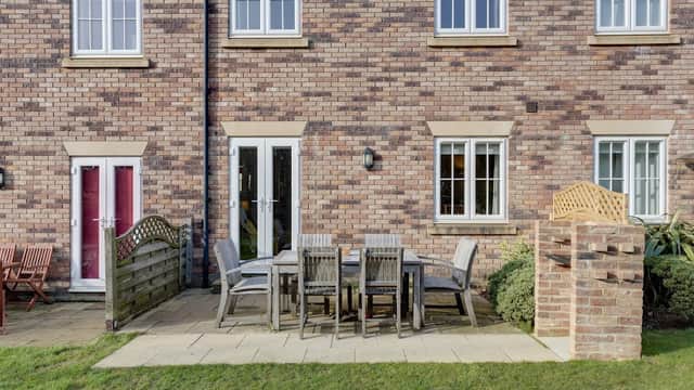 Brick cottage exterior with patio furniture, a wooden fence, and well-maintained greenery in Filey, Yorkshire.