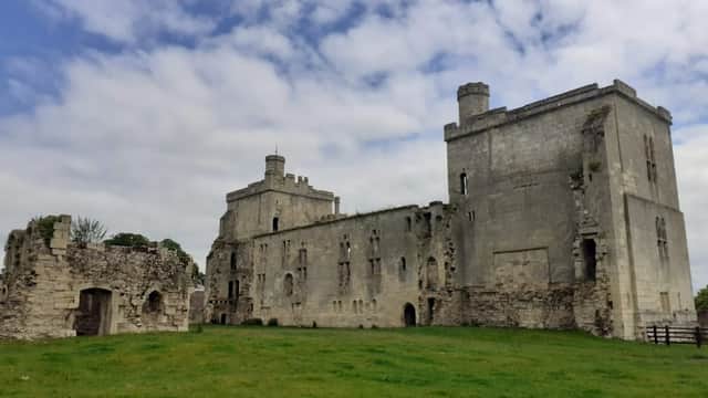 Ruins of Wressle Castle featuring stone walls, towers, and grassy grounds under a cloudy sky.
