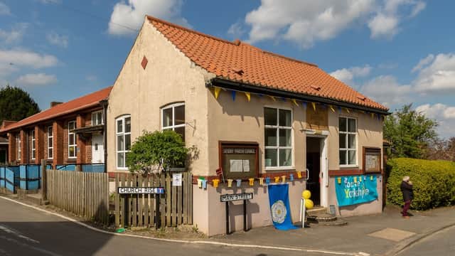 Skidby Parish Council building with colorful bunting, signs for Church Rise and Main Street, and a clear blue sky.