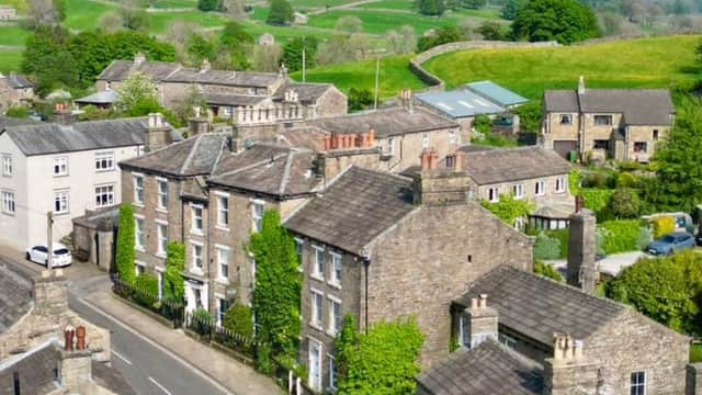Aerial view of Middle House in Askrigg, surrounded by stone buildings and lush green hills in Cubeck, Yorkshire.
