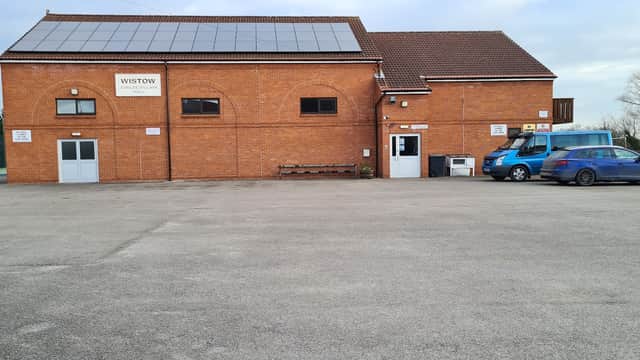 Wistow New Jubilee Village Hall with solar panels, parking area, and a blue vehicle beside the entrance.