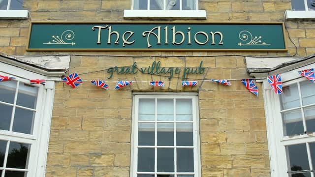 The Albion restaurant sign with Union Jack bunting and large windows on a stone building in Clifford, Yorkshire.