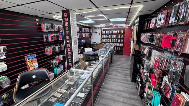 Inside a printing shop with display cases, various phone accessories, and a repair area in a modern setting.