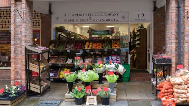 Colorful display of fruits, vegetables, and flowers outside a shop with a welcoming entrance in Beverley, Yorkshire.
