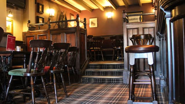 Wooden furnishings and a cozy atmosphere with a carpeted floor and warm lighting in a pub setting.