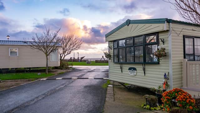 A holiday park with caravans, a paved road, and colorful flowers under a cloudy sky in Tunstall, Yorkshire.