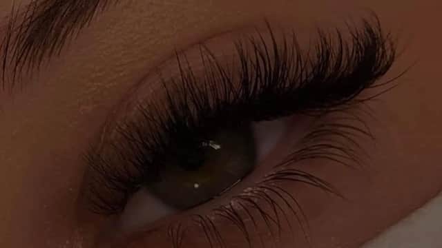 Close-up of a woman's eye showcasing long, voluminous eyelashes and a well-groomed eyebrow.