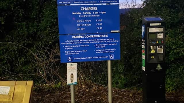 Sign for Station Road Car Park with parking fees, hours, and payment machine in Holme Valley, Yorkshire.