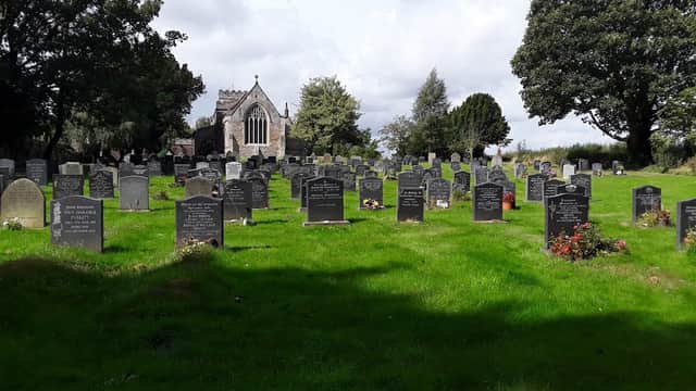 St Mary's Church surrounded by a lush graveyard filled with headstones under a cloudy sky.