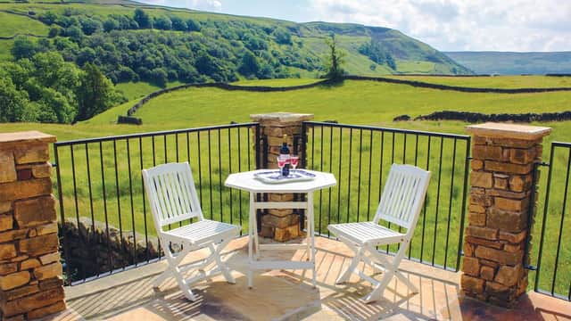 Cozy patio with white chairs and a table overlooking lush green hills and stone walls in West Stonesdale, Yorkshire.