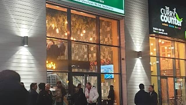 My Peshawar restaurant entrance at night, with people gathered outside and illuminated signage.