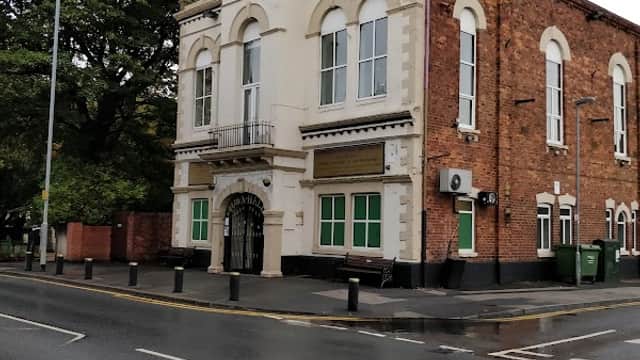 Knottingley Town Hall Community Centre features a brick facade, clock tower, green windows, and a tree-lined street.