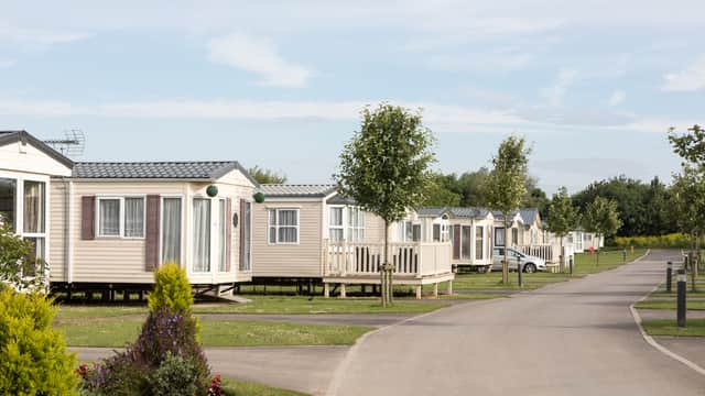 Row of holiday caravans along a paved road, surrounded by green grass and trees at Skipsea Sands Holiday Park.