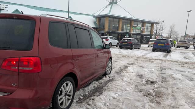 Red vehicle parked in a snowy Pay & Display lot outside a Morrison's store in Barnsley, Yorkshire.