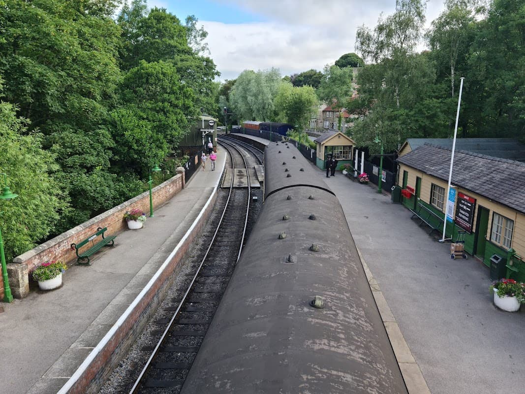 North Yorkshire Moors Railway car park with tracks, greenery, and historic station buildings in Pickering, Yorkshire.
