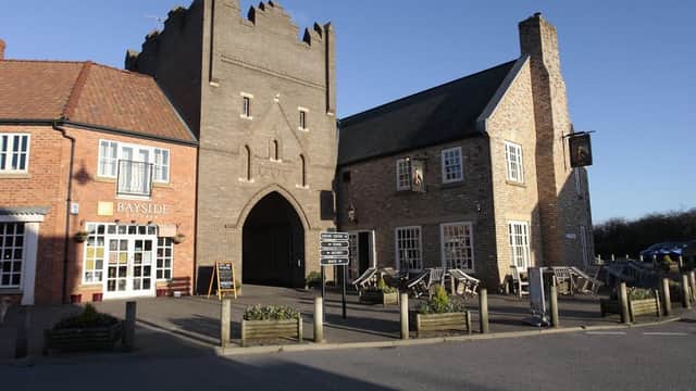 The Happy Plaice Beach House features a unique castle-like structure with outdoor seating and nearby shops.