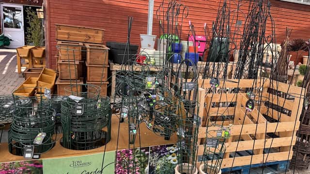Plant supports and gardening supplies displayed on wooden pallets at Victoria Farm Garden Centre, surrounded by various pots.