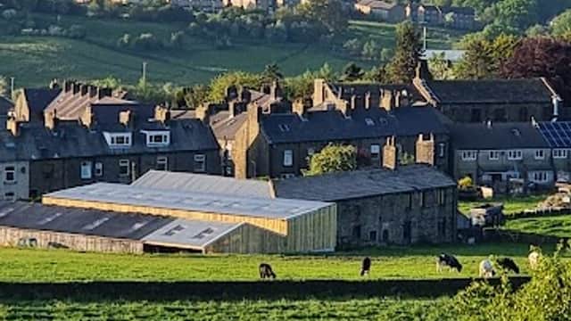 Cullingworth Village Hall surrounded by green fields and stone buildings, with hills in the background.