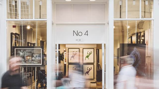 Gallery entrance with large windows displaying framed art, people walking past, and the name "Castle Fine Art" prominently featured.