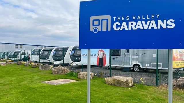 Sign for Tees Valley Caravans Ltd outside a shop showcasing multiple caravans on display in a grassy area.