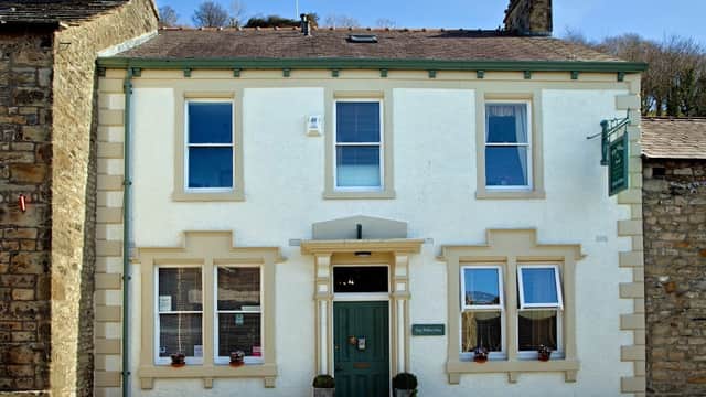 Charming guest house with white exterior, green door, and window boxes, set in a stone village in North Yorkshire.