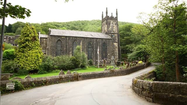 Historic stone church with a tall spire, surrounded by greenery and a winding road in Cragg Vale, Yorkshire.