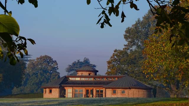 A modern brick building with a circular roof surrounded by trees and a frosty lawn in Escrick, Yorkshire.
