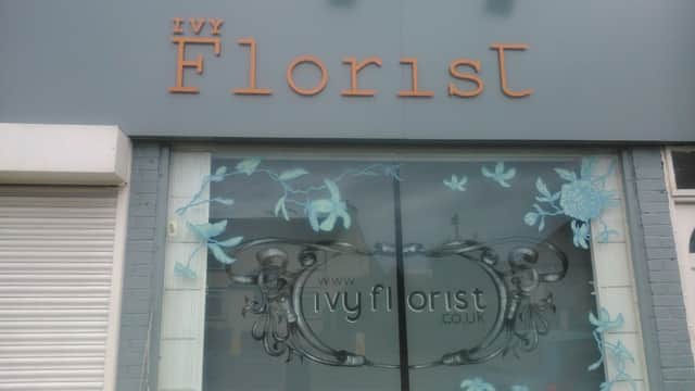 Signage for Ivy Florist with floral designs on the window and a website address displayed prominently.